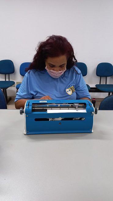 Mulher adulta escrevendo em uma máquina de braille.