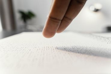 Imagem com foco no dedo indicador e médio fazendo leitura em braille