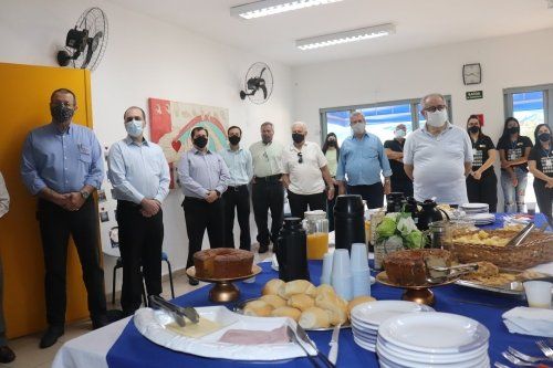 Um grupo de pessoas está em pé ao redor de uma mesa com comida.