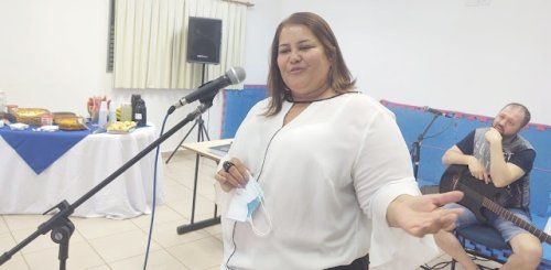 Uma mulher está parada em frente a um microfone em uma sala.