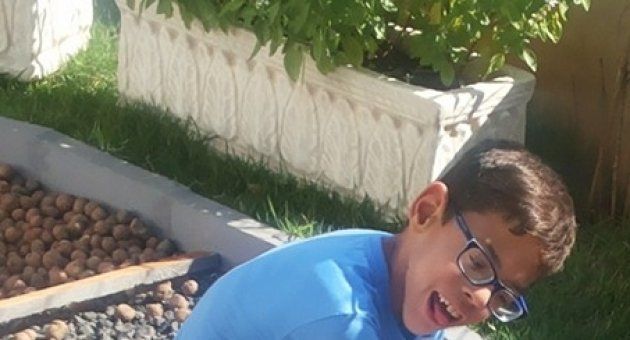 Um menino de óculos está sentado na grama.