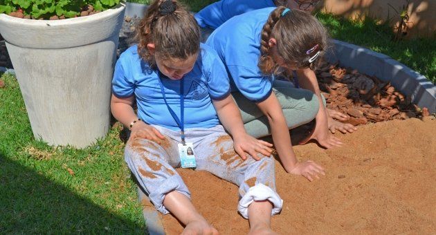 Duas meninas estão brincando em uma caixa de areia.