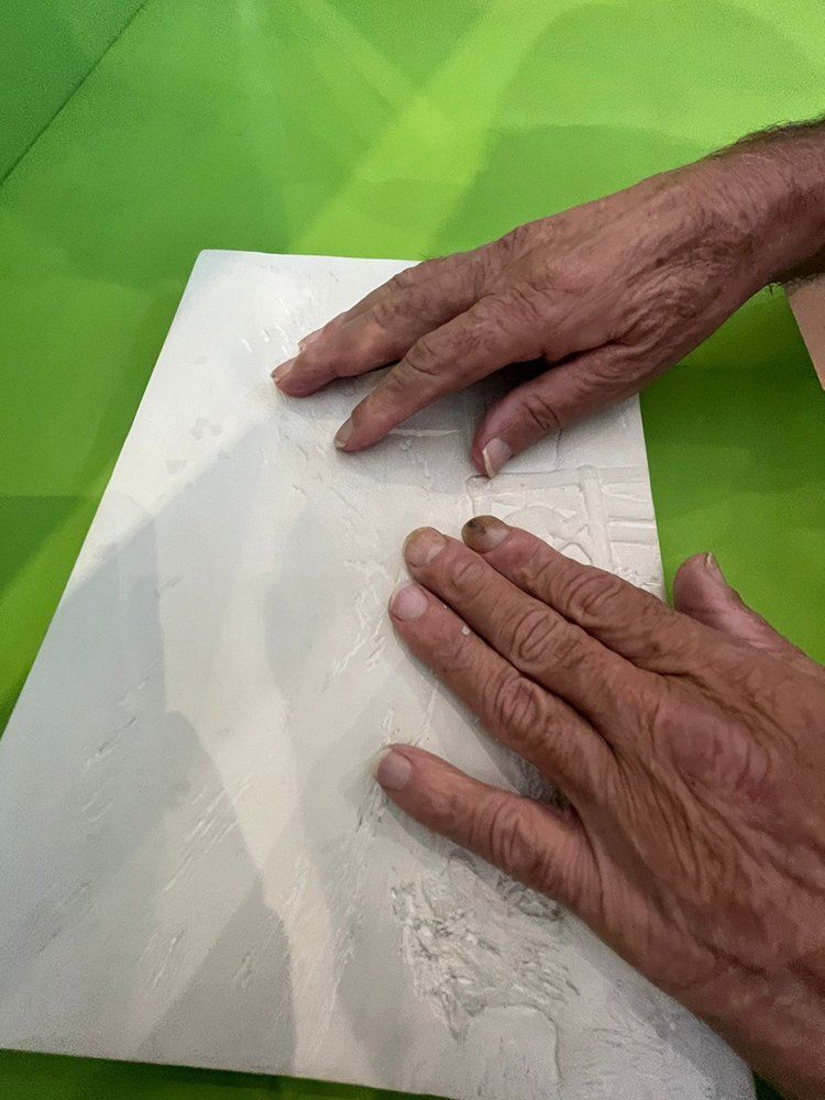Mãos de uma pessoa idosa tateando uma tela em relevo.