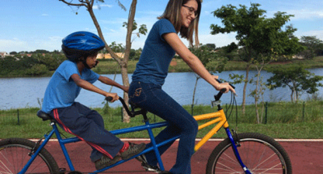 Uma mulher e uma criança estão andando de bicicleta dupla.
