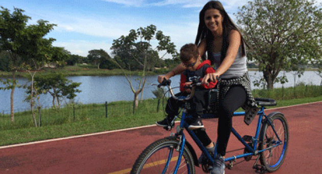 Uma mulher e uma criança estão andando de bicicleta dupla.