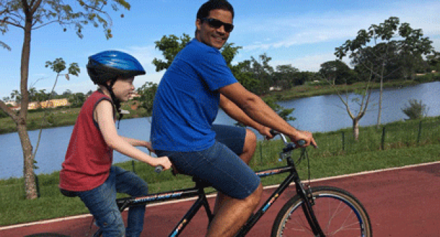 Um homem está andando de bicicleta com uma criança na garupa.