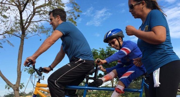 Um homem está andando de bicicleta com uma criança na garupa.