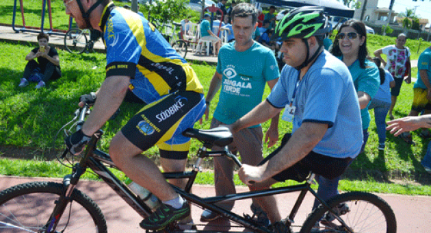 Um homem está andando de bicicleta dupla com outro homem sentado nela.