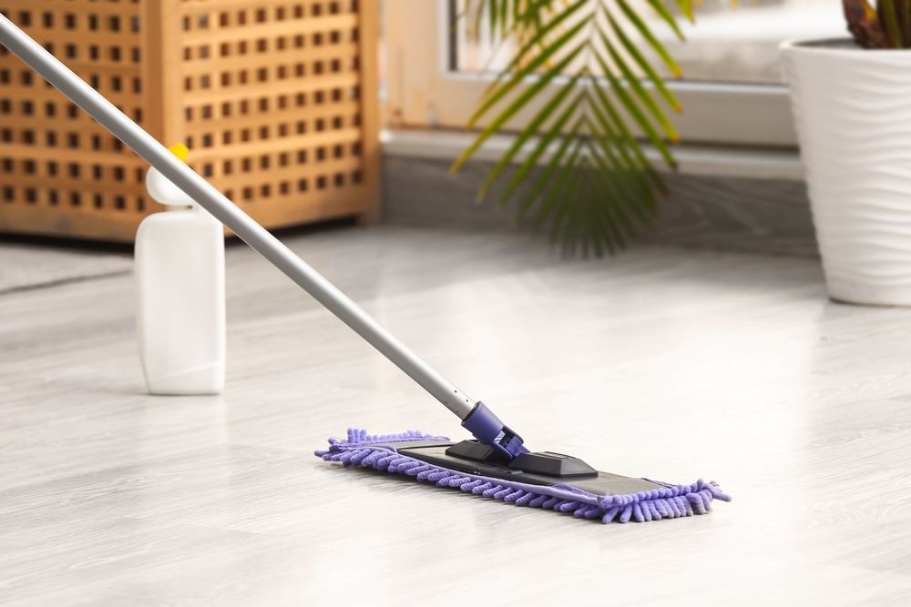 A mop is being used to clean a wooden floor.