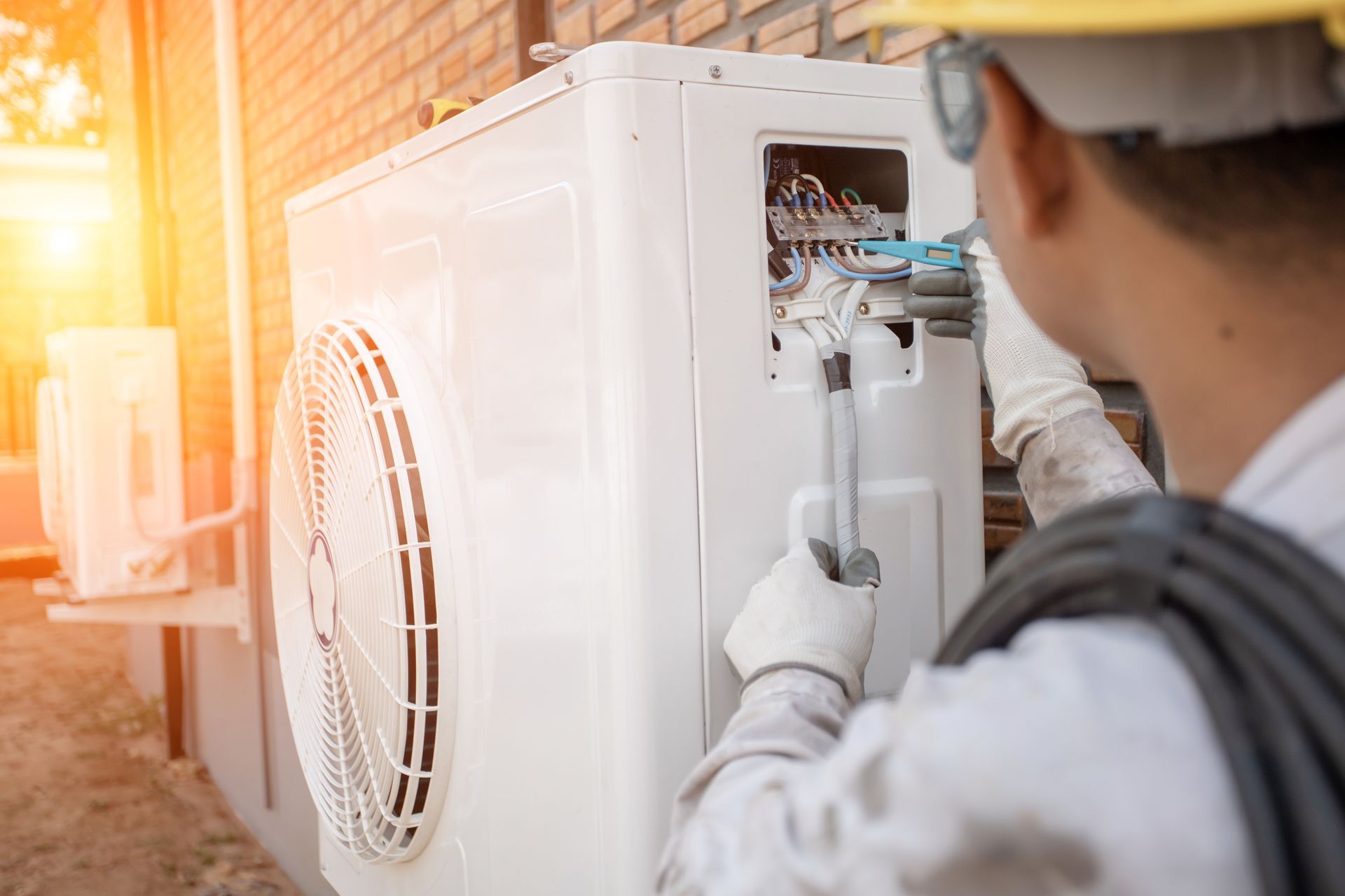 A man is fixing parts of an HVAC system with a wrench.