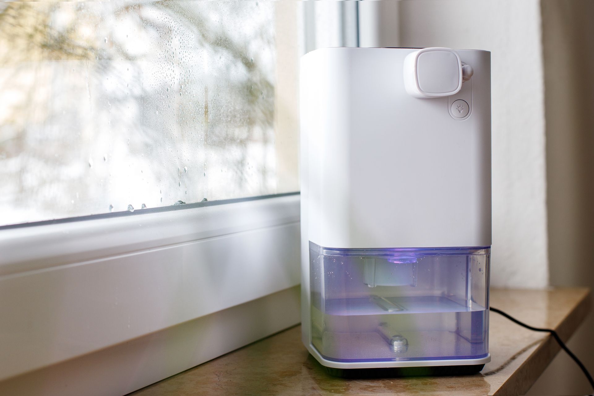 A white humidifier is sitting on a window sill next to a window.