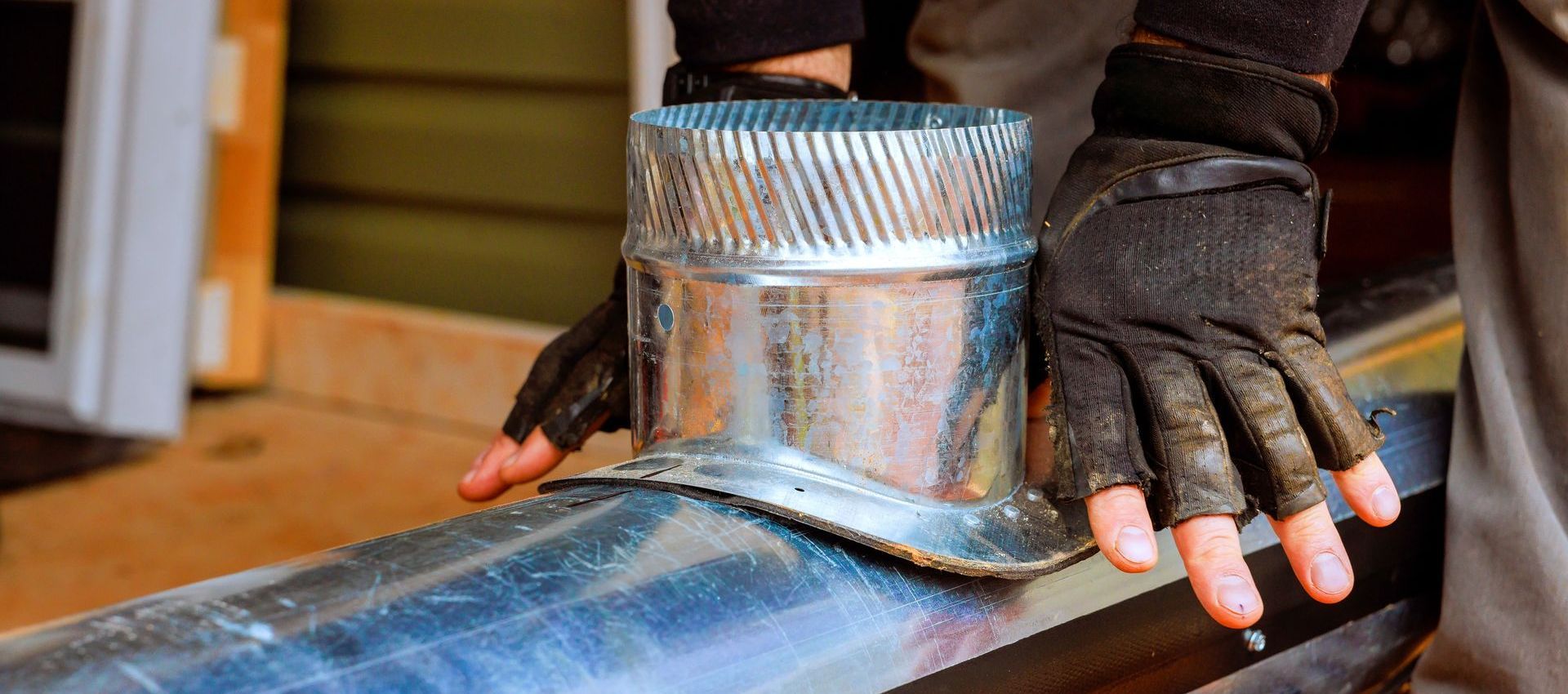 A person wearing gloves is holding a metal pipe.