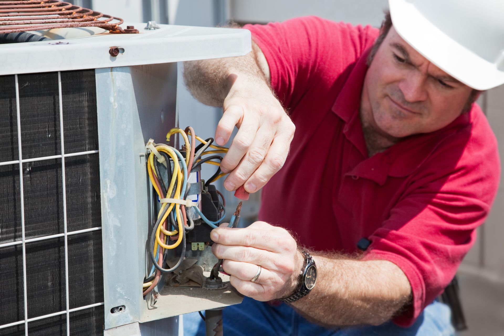 A man is working on an air conditioner with a screwdriver.
