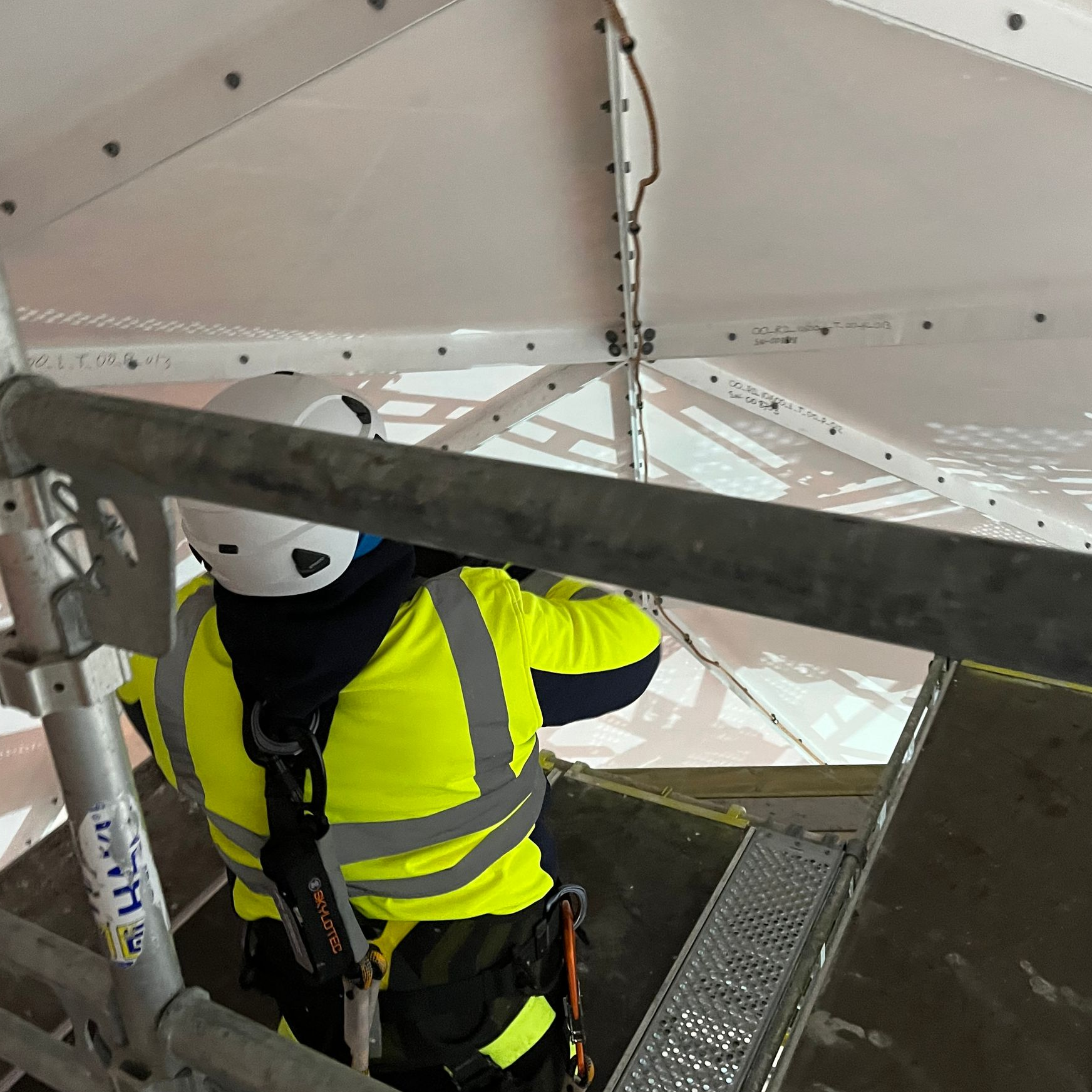 Back of worker in high vis jacket working on the rear of a satellite dish. 