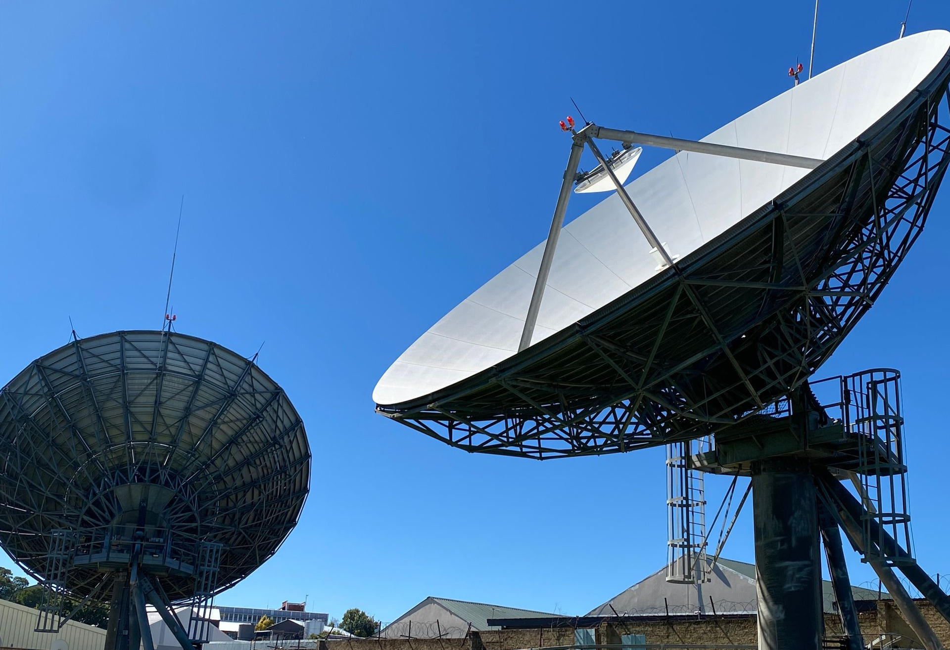 Two satellite antenna set against a blue sky