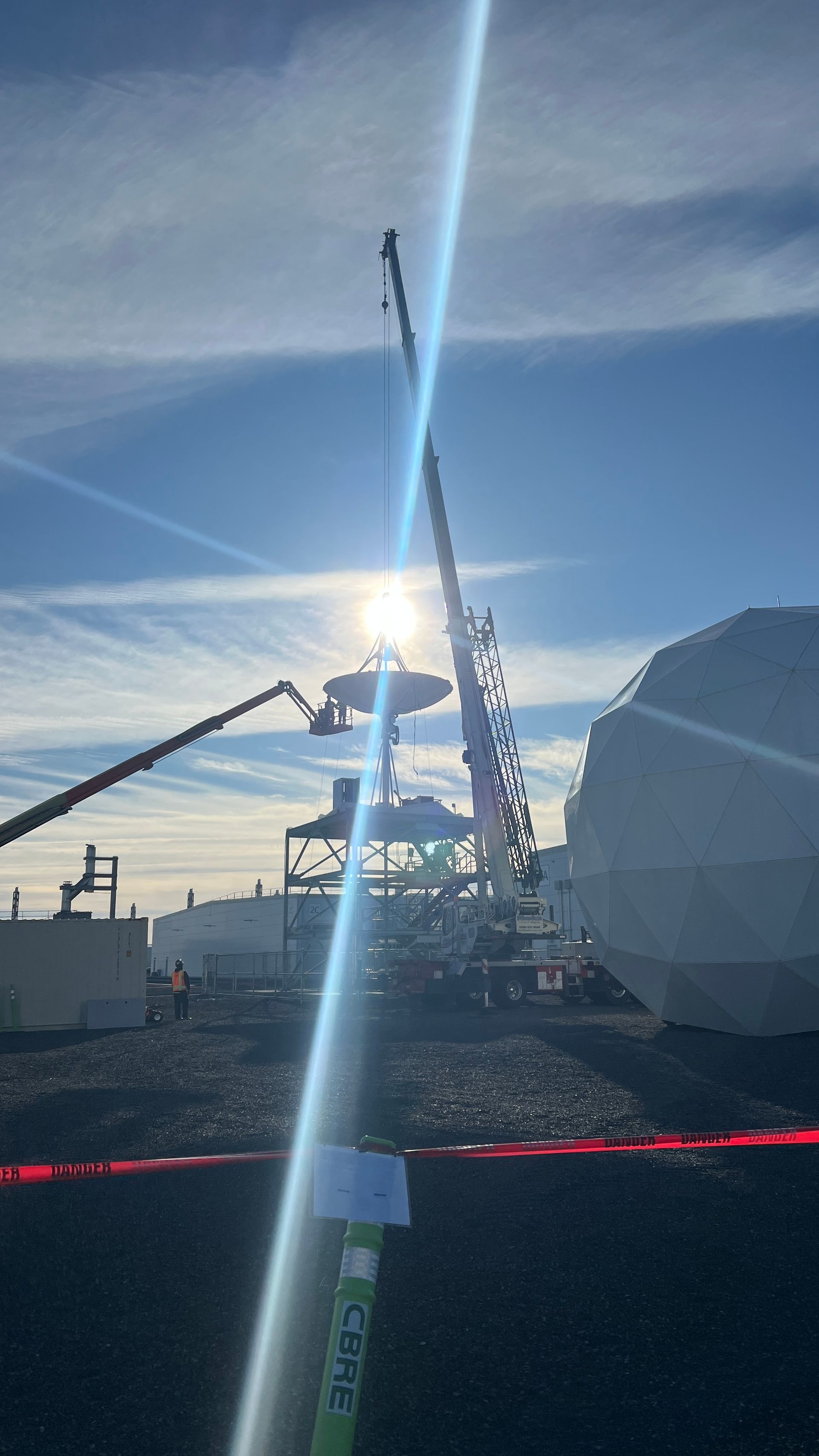 Satellite antenna being craned onto a platform with sun ray