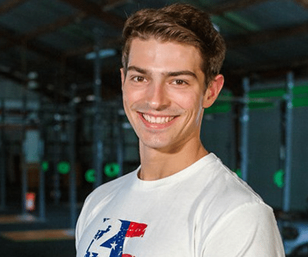Smiling person in a white T-shirt standing in a gym or training facility