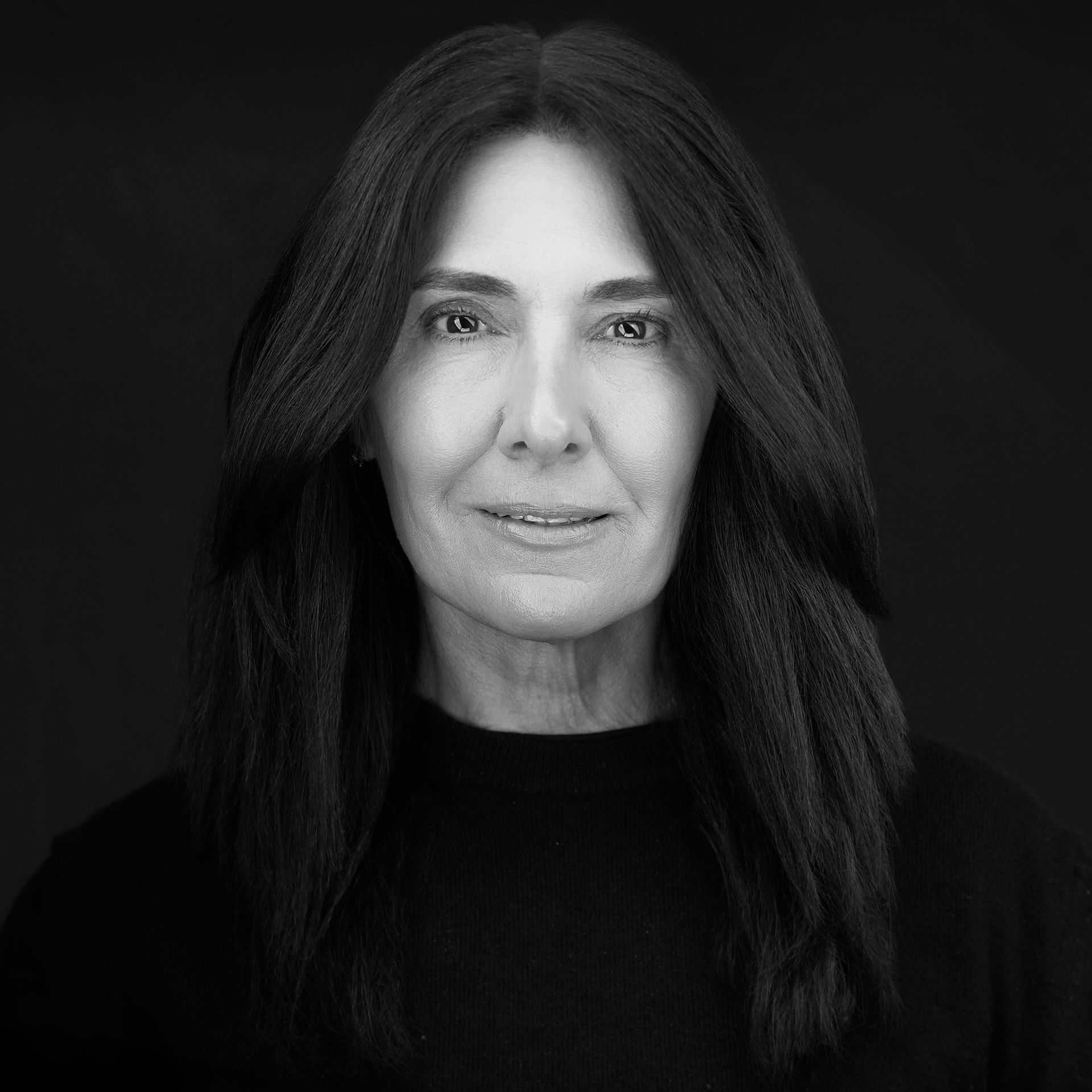 A woman with long hair is smiling in a black and white photo.