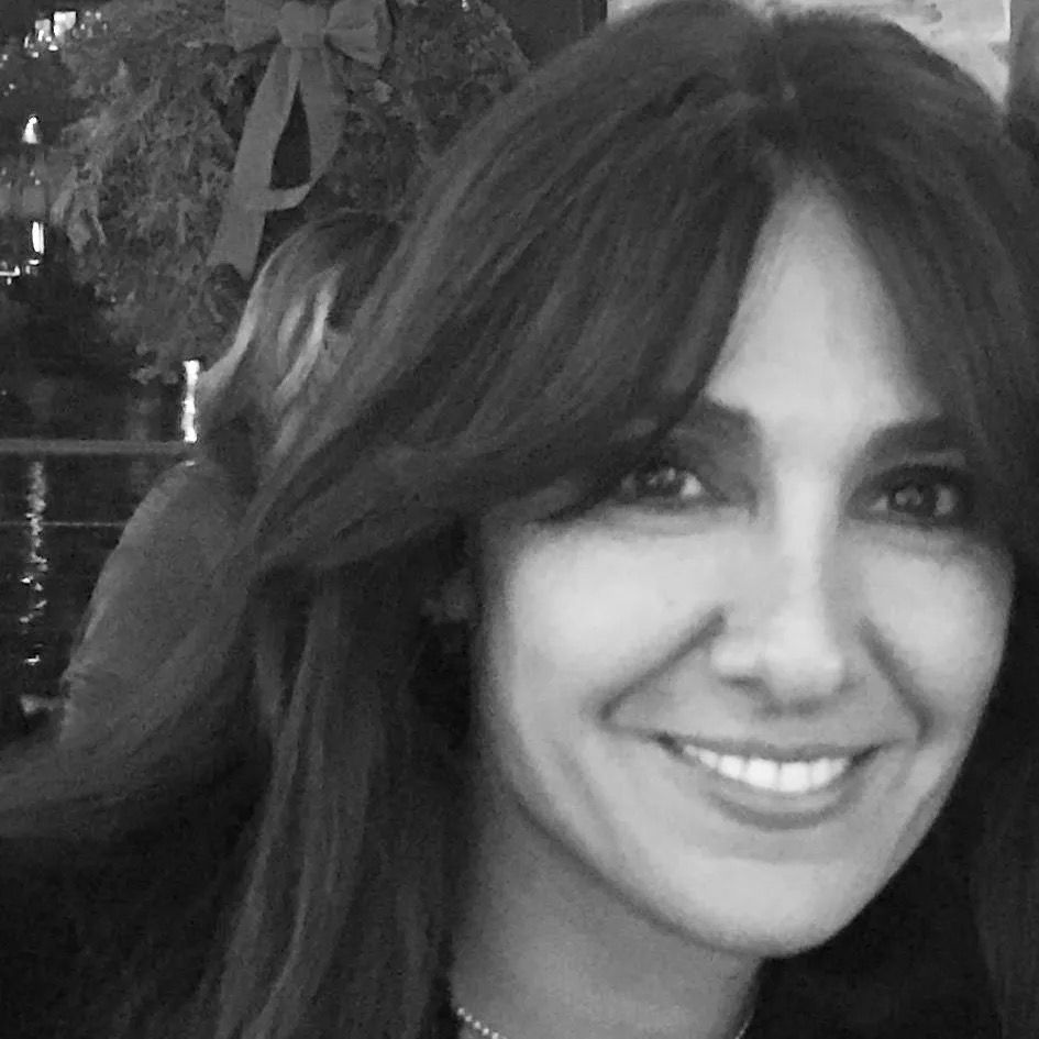 A woman with long hair is smiling in a black and white photo.