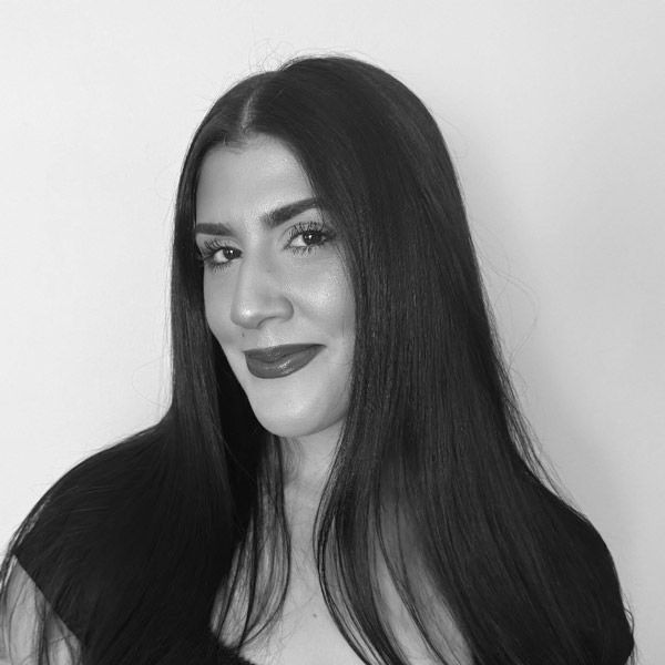 Woman with long dark hair, smiling, wearing dark lipstick. Maria at Hustlestop Newton MA