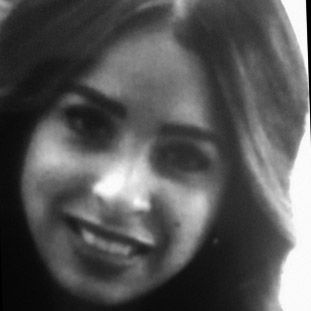 Woman smiling, dark hair, black and white photograph, slightly blurred.