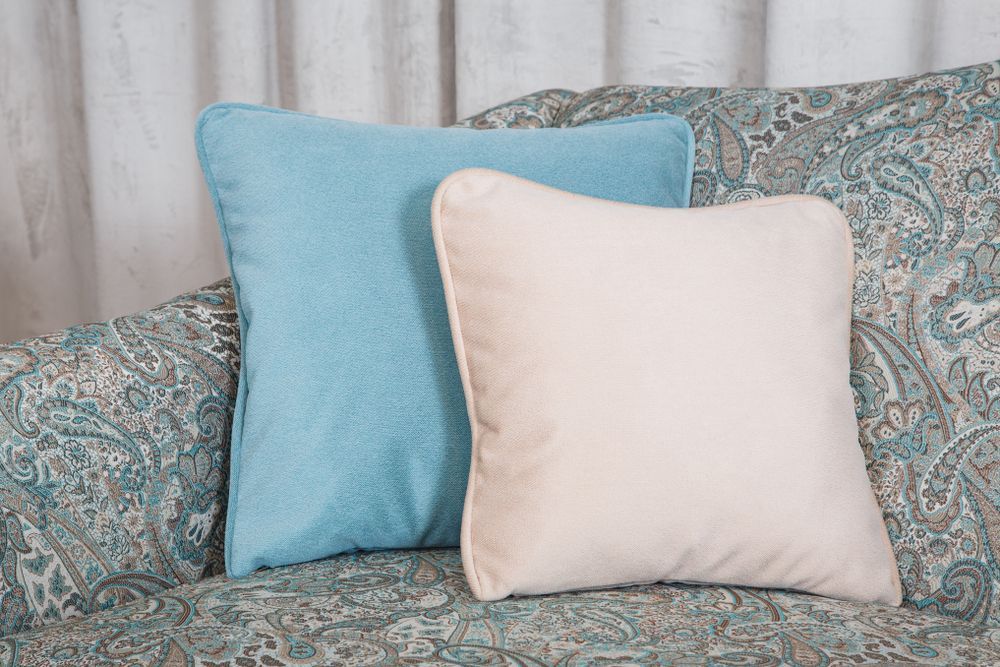 Two Throw Pillows on a Paisley Sofa One Blue and One Cream — Atherton Decor Centre In Tolga, QLD