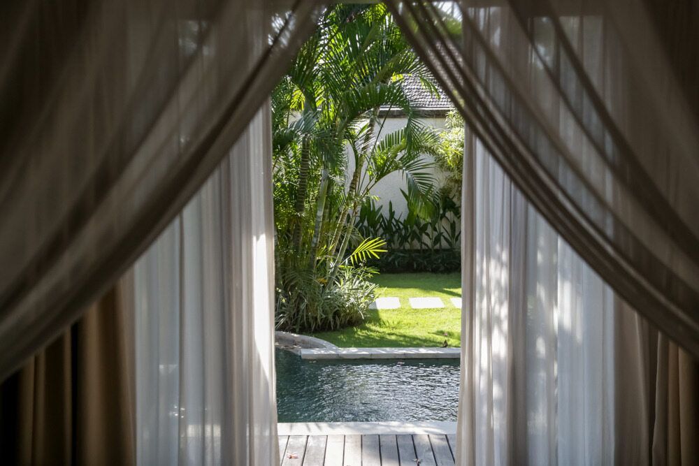A View of a Swimming Pool Through a Window With Curtains — Atherton Decor Centre In Atherton, QLD