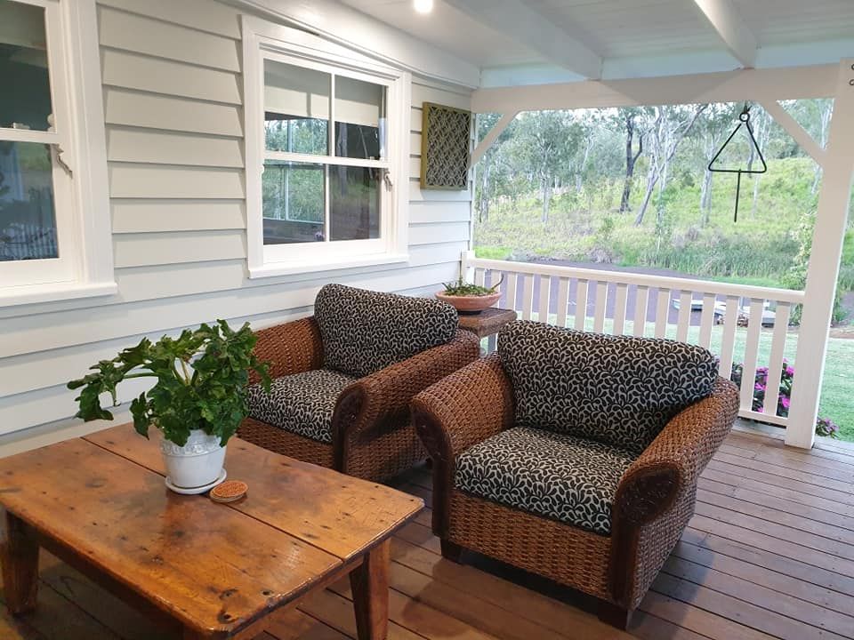 A Porch With Two Chairs and a Table With a Potted Plant on It — Atherton Decor Centre In Atherton, QLD