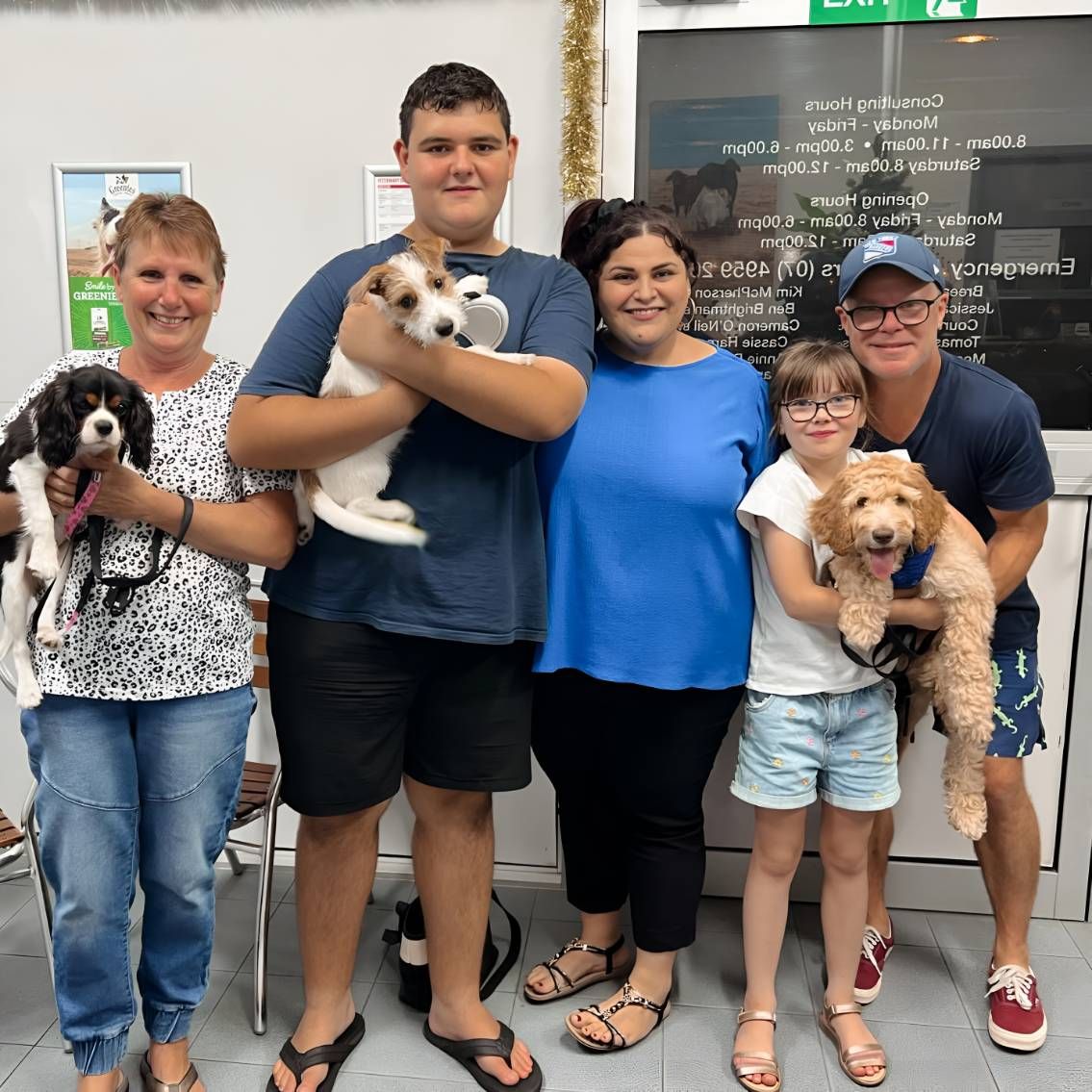 A Group Of People Standing Next To Each Other Holding Dogs — Valley Vet Surgery In Walkerston, QLD