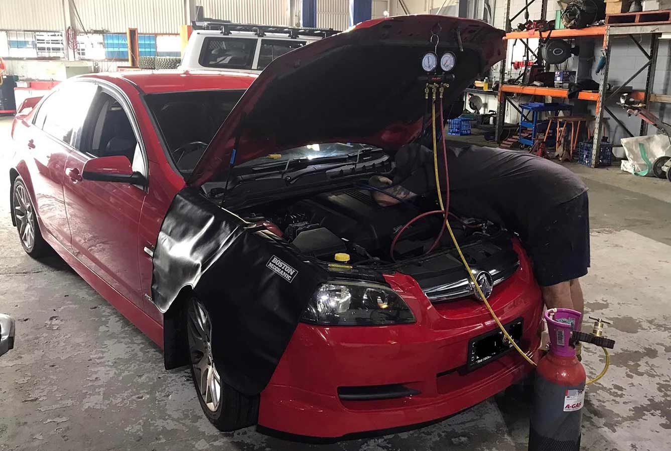 A Man is Working on a Red Car With the Hood Open in a Garage — OG Diesel NQ in Garbutt, QLD