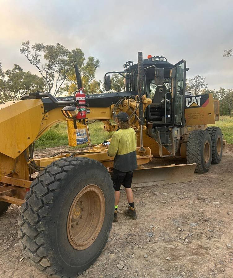 A Man is Standing Next to a Large Yellow Cat Tractor — OG Diesel NQ in Garbutt, QLD