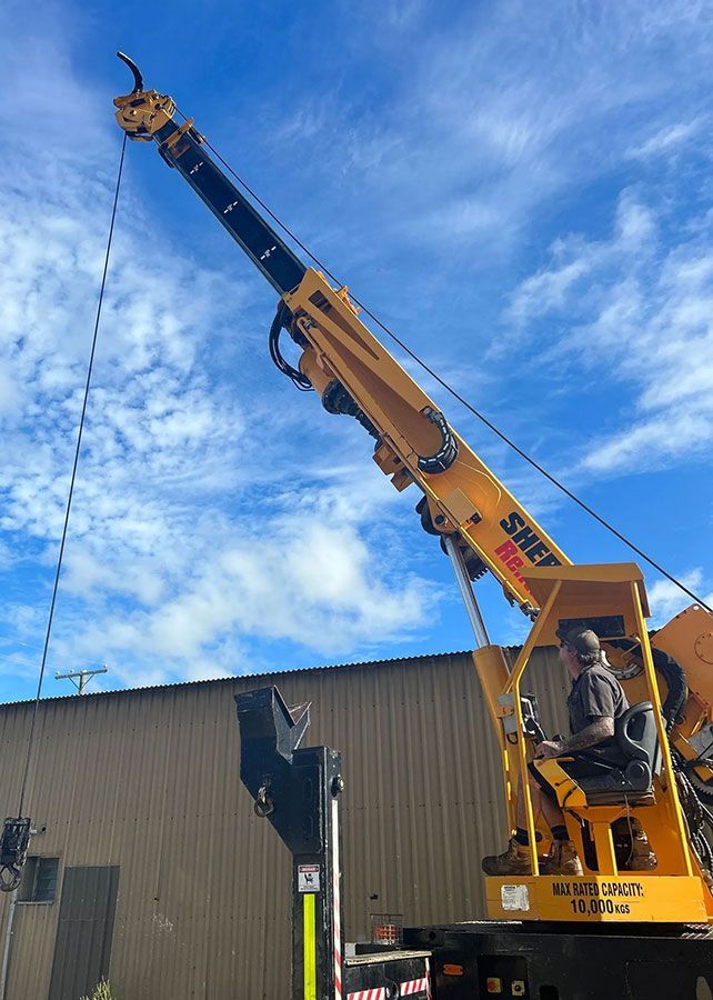 A Man is Driving a Yellow Crane in Front of a Building — OG Diesel NQ in Garbutt, QLD