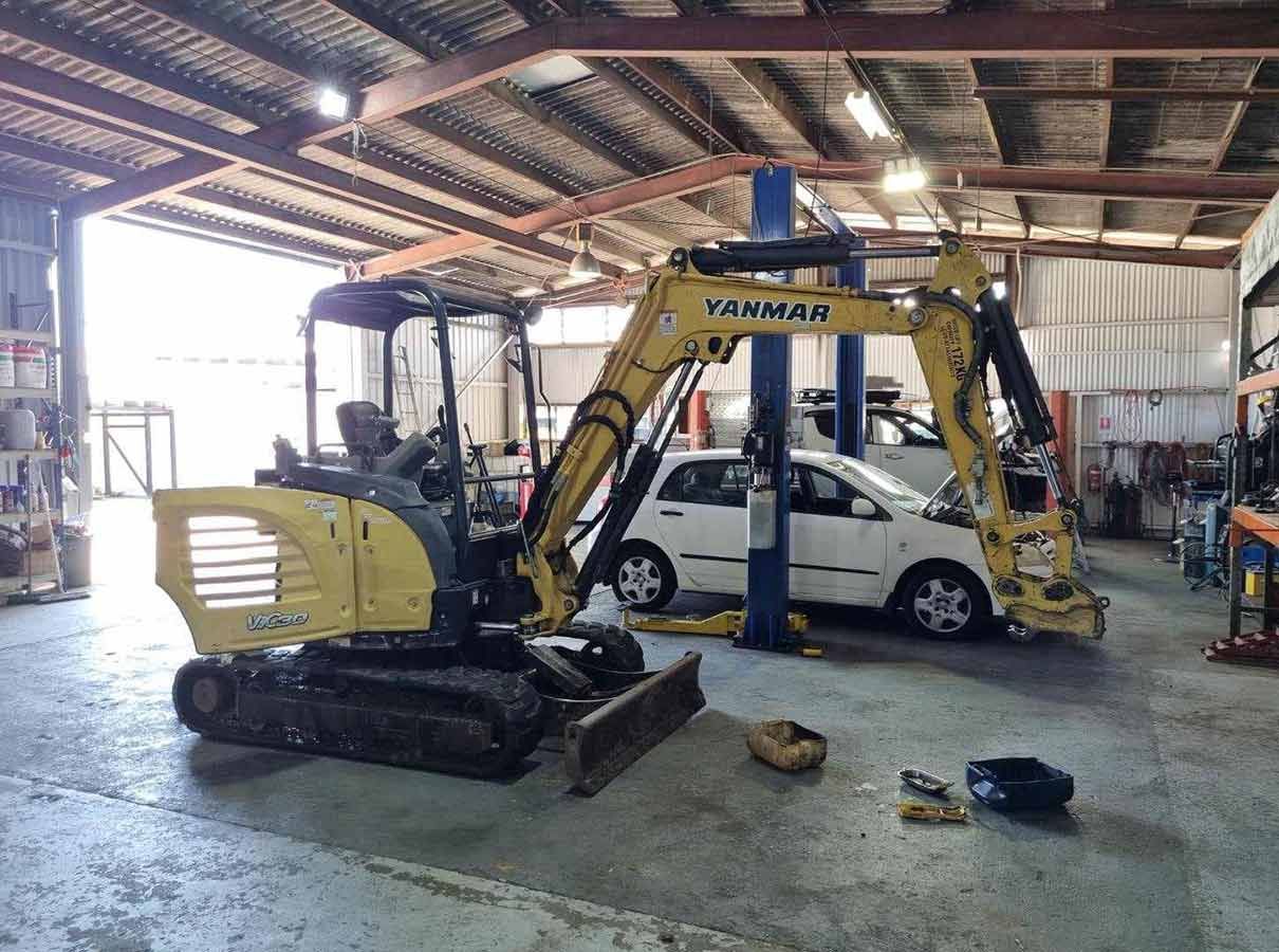 A Small Excavator is Sitting in a Garage Next to a Car — OG Diesel NQ in Garbutt, QLD
