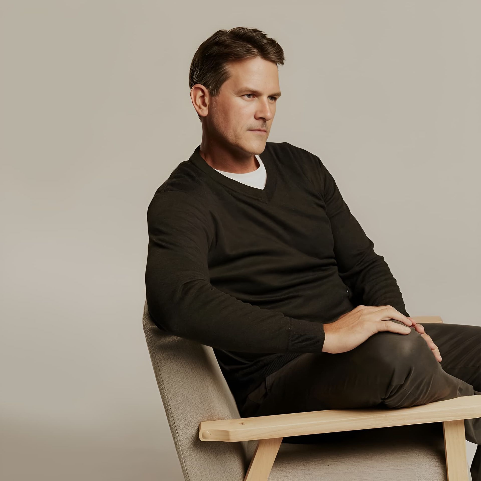 A Man in a Black Sweater is Sitting in a Chair — Bonanno's Menswear in Kiama, NSW