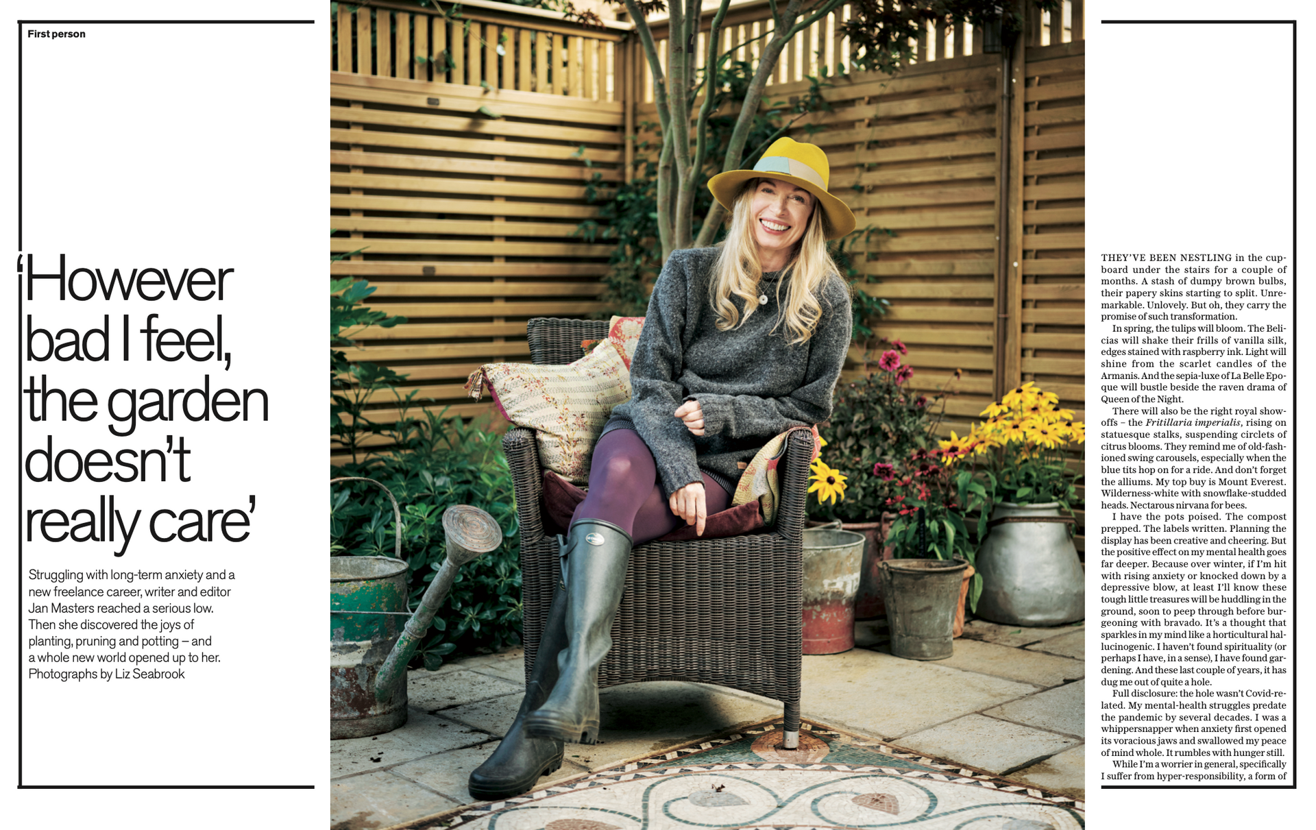 A person in a yellow hat, sweater, and boots sits in a garden chair, surrounded by potted plants and a wooden fence.
