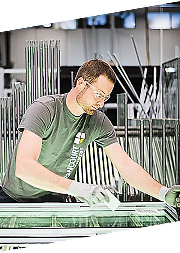 Un homme travaille sur un morceau de verre dans une usine.