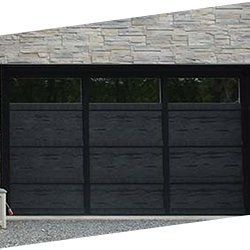 Une porte de garage noire se trouve devant un mur de pierre.