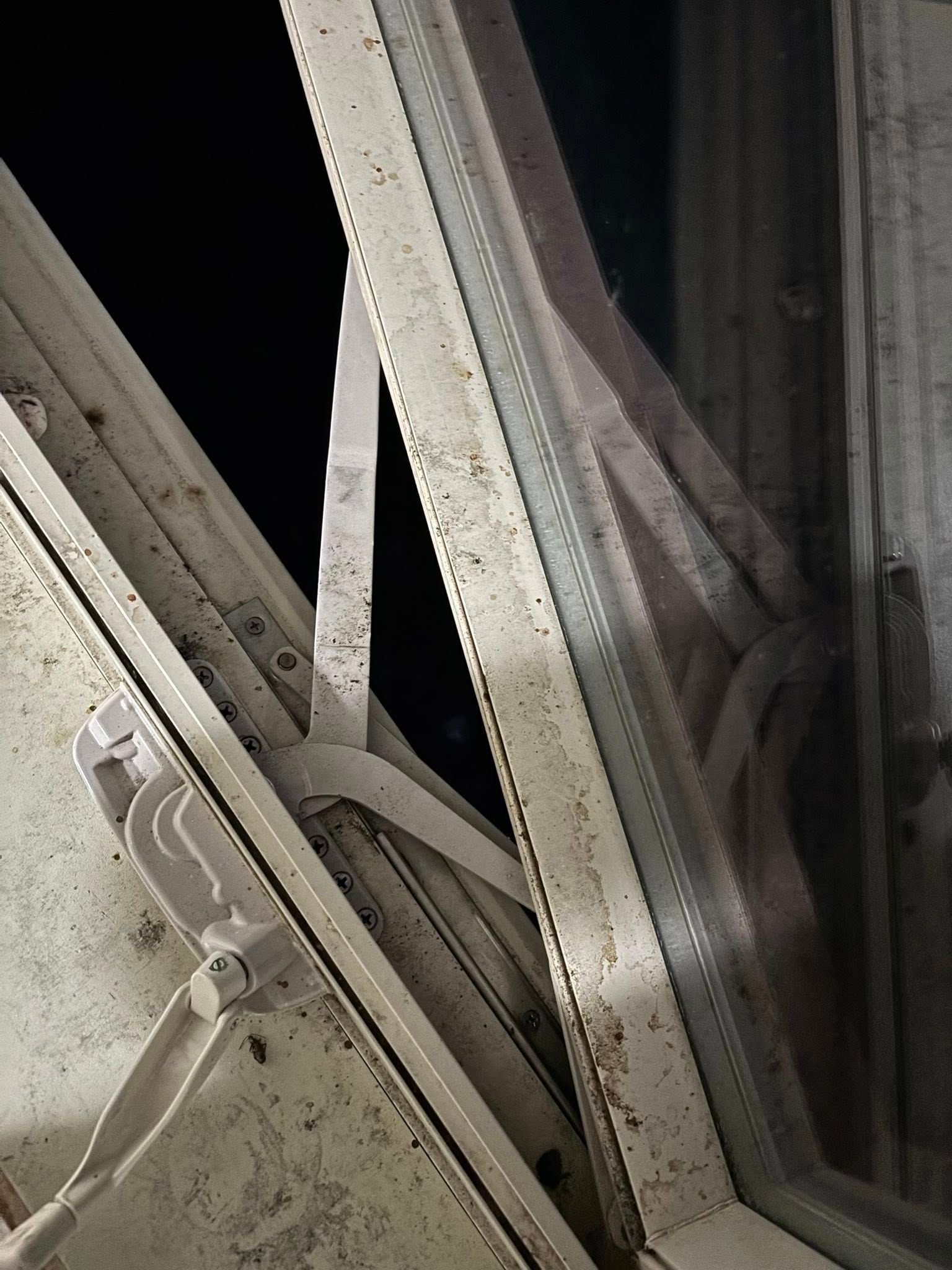 Open, white-framed window, with a black background visible. The frame has a crank to open and close.