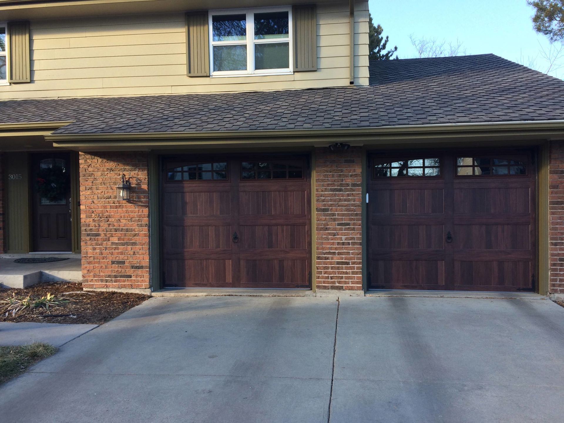 A brick house with three garage doors and a concrete driveway.