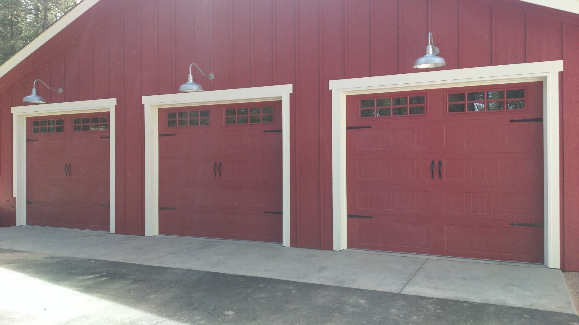 Red barn-style garage doors with white trim and overhead lights.