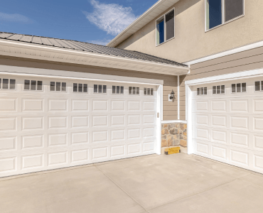 There are two garage doors on the side of a house.