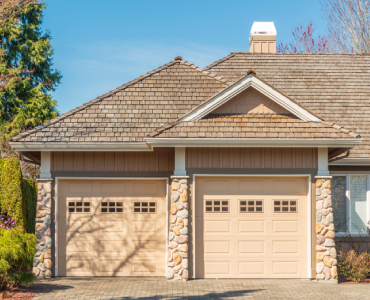 A house with two garage doors and a shingle roof.