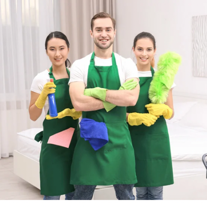 A man and two women in green aprons are standing next to each other holding cleaning supplies.