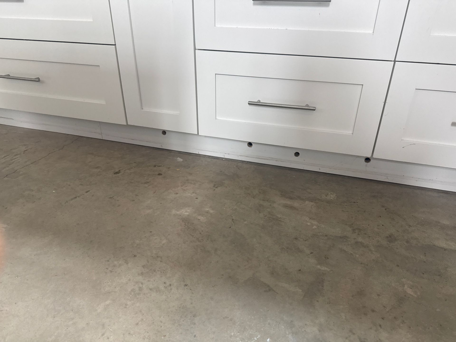 A kitchen with white cabinets and a concrete floor
