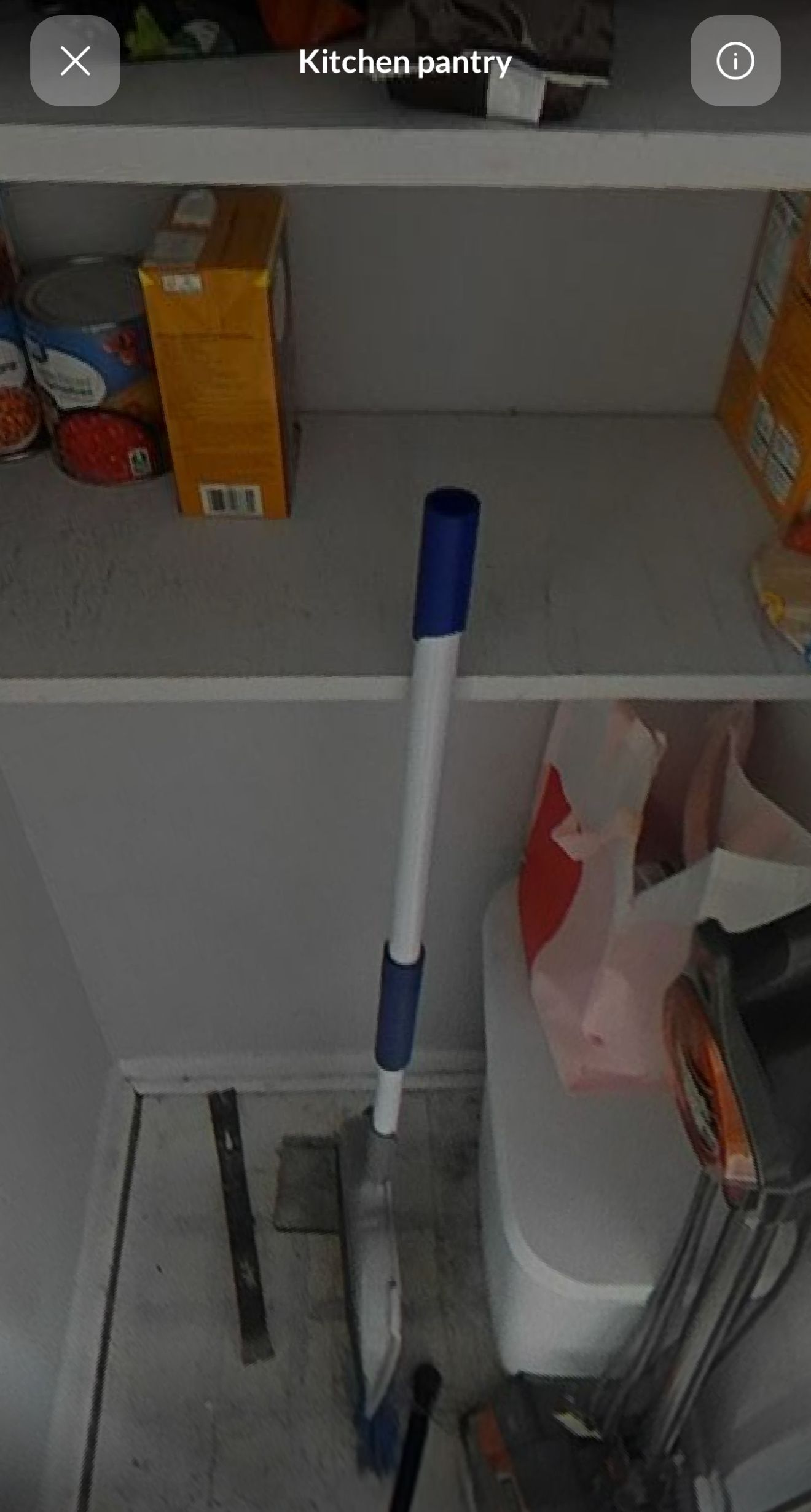 A mop is sitting on top of a shelf in a pantry.