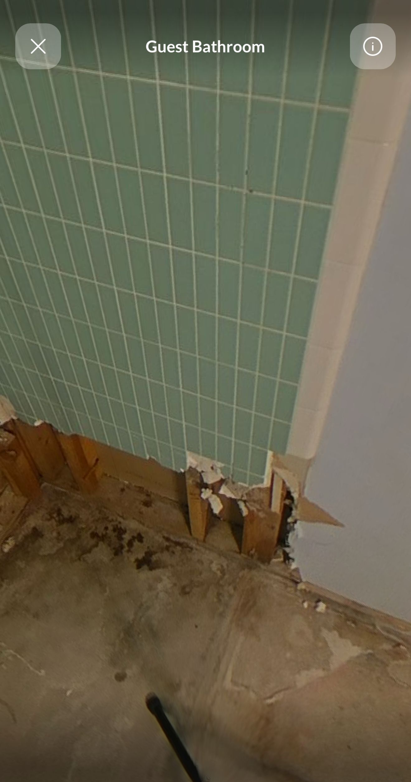 A bathroom with green tiles and a hole in the wall.