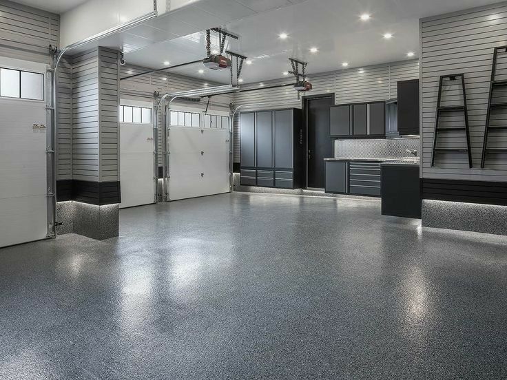 A large empty garage with a gray floor and black cabinets.