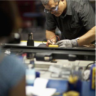 Un homme portant des gants travaille sur un appareil électronique