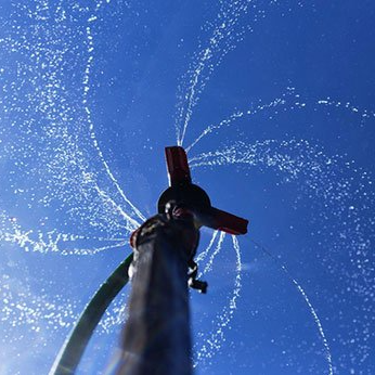 Un tuyau pulvérise de l'eau contre un ciel bleu