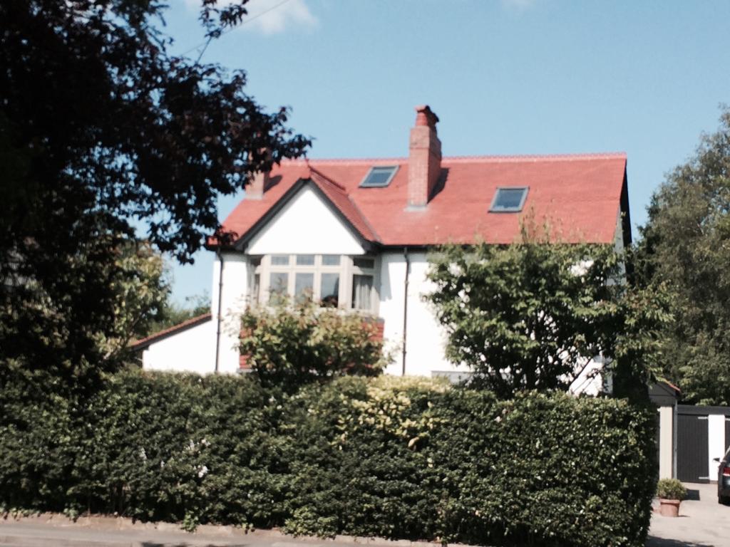 A picture of a new red tile roof on a white rendered detached property carried out by Roofers Manchester